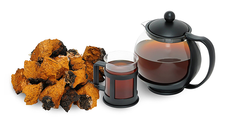 A drink made from chaga in a coffee pot with chaga pieces next to it